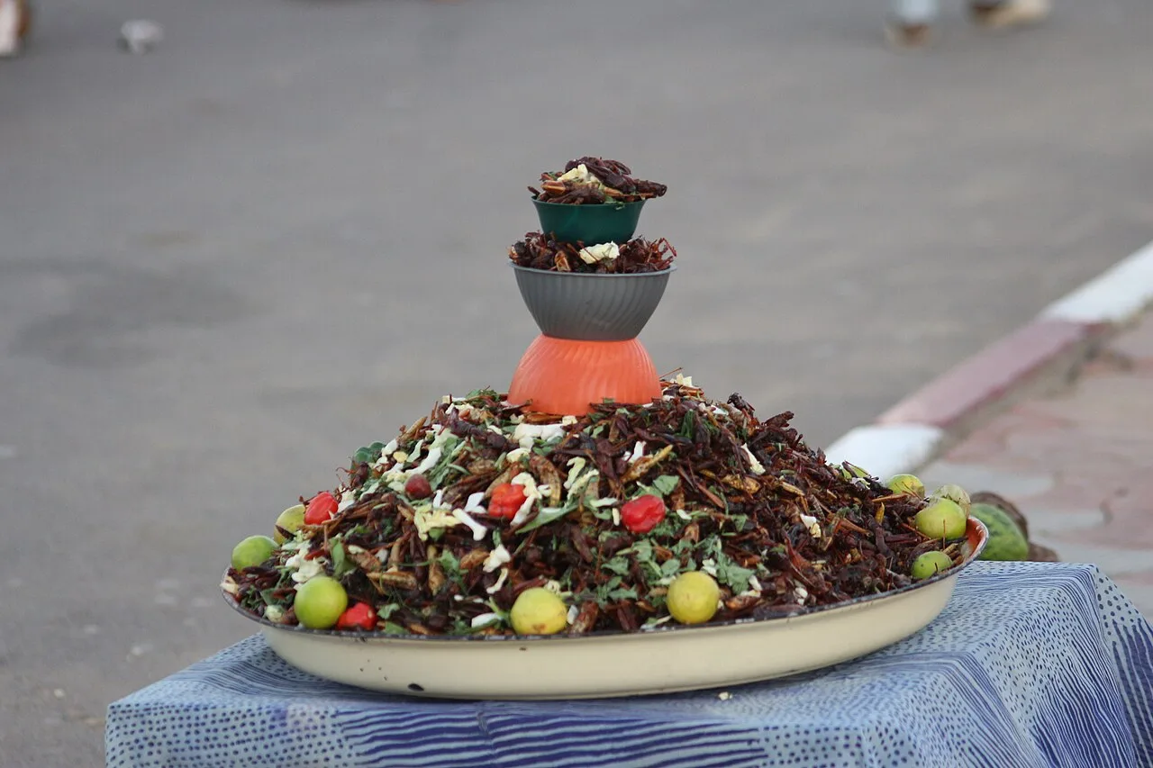 Жареная саранча с зеленью и овощами на большом блюде